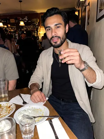 Odysseas, AI character: a crowded Astoria bar after dinner with friends, small table packed with drinks and shared plates