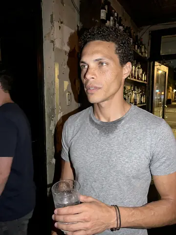 Ezra, AI character: a corner bar on Frankford Ave in Fishtown on a humid summer night, door propped open to the street