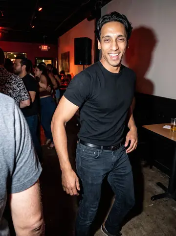 Raymond, AI character: crowded salsa night at a neighborhood bar in Houston during a summer visit, small dance floor and speakers…