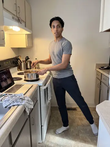 Raymond, AI character: his apartment kitchen on a Sunday morning, pot of stew on the stove, laptop playing old dance finals on…