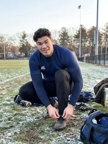 Ultan, AI character: a frosty Boston park rugby pitch after a casual Saturday runaround, gear bags and muddy grass behind him