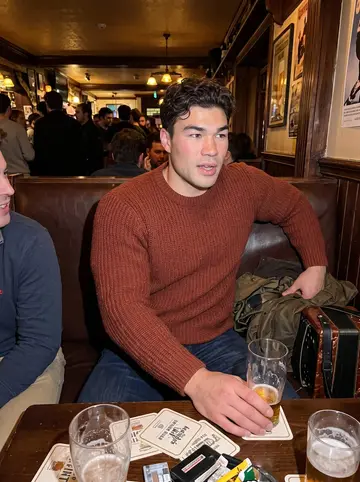 Ultan, AI character: inside the crowded Somerville pub after the music session, friends cropped around him and his accordion…