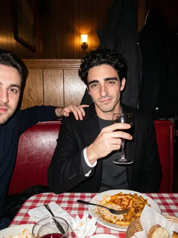 Matteo, AI character: a red-booth Italian-American restaurant in Newark's North Ward on a December night, checked tablecloth and…