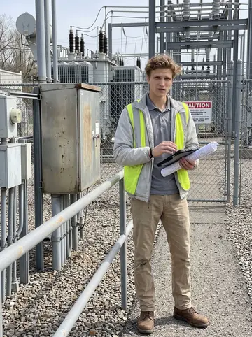 Oscar, AI character: a fenced utility substation walkway outside Pittsburgh during a daytime site check