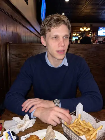 Joey, AI character: a casual Columbus sports bar during a college football game, wood booth, TV glow, half-finished fries on…