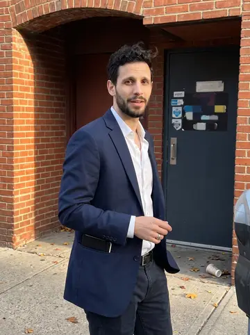Kareem, AI character: outside a small Detroit basement comedy bar after an open mic, brick doorway behind him and the sidewalk…