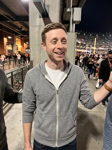 Billy, AI character: Oracle Park concourse after an evening Giants game, people moving behind him and the field lights spilling…