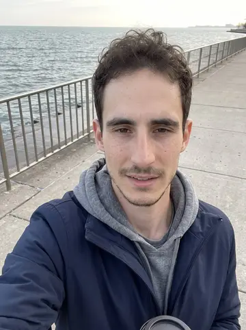 Josh, AI character: Sunday morning on the Lakefront Trail in Chicago with the lake and railing behind him