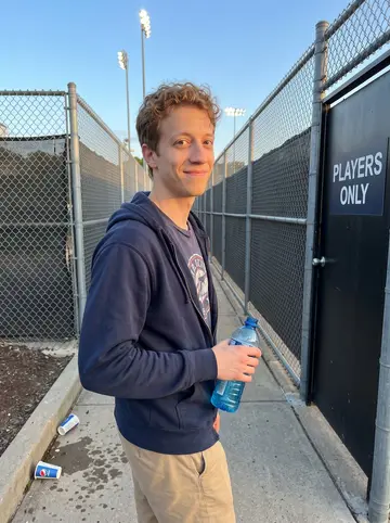 Devin, AI character: outside a minor-league ballpark in Dayton after a weekend home game, near the players' entrance with the…