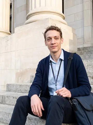 Andy, AI character: outside the Monroe County courthouse in Rochester after work, sitting on the stone steps with his bag…