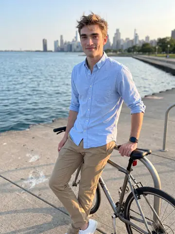 Dillon, AI character: the Chicago lakefront path near Belmont Harbor at golden hour, his bike leaned against the rail beside him