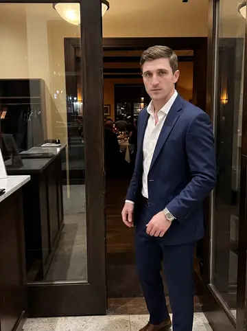 Richard, AI character: inside a downtown Dallas restaurant lobby on a cold night, dark wood doorway, coat check counter and…