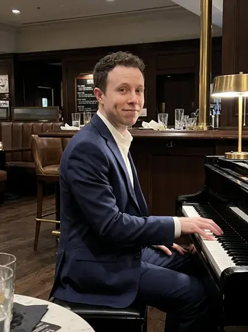 Jaylen, AI character: the corner piano in a quiet Atlanta hotel lobby bar after his late set, dark wood bar and brass lamps…