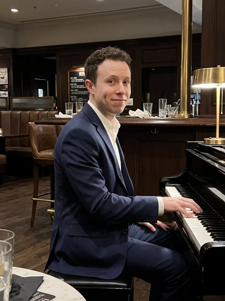 Jaylen, AI character: the corner piano in a quiet Atlanta hotel lobby bar after his late set, dark wood bar and brass lamps…