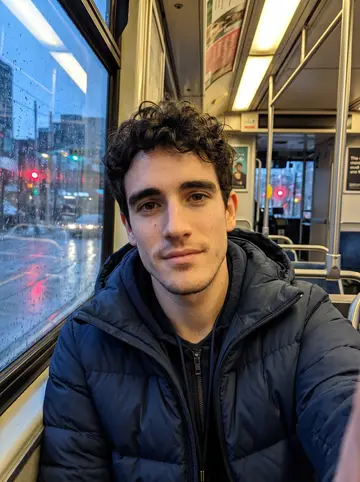 Ali, AI character: inside a Toronto streetcar after work during blue hour, wet windows and city lights sliding past behind him