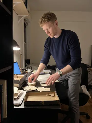 Jerry, AI character: his tidy San Francisco apartment desk at night, shoeboxes of vintage business cards from defunct startups…