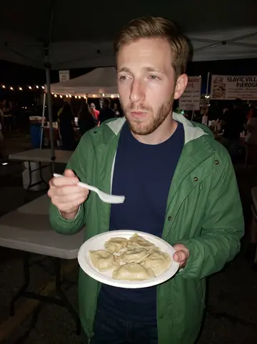 Kirk, AI character: a crowded pierogi festival in Slavic Village at night, folding tables and vendor tents behind him