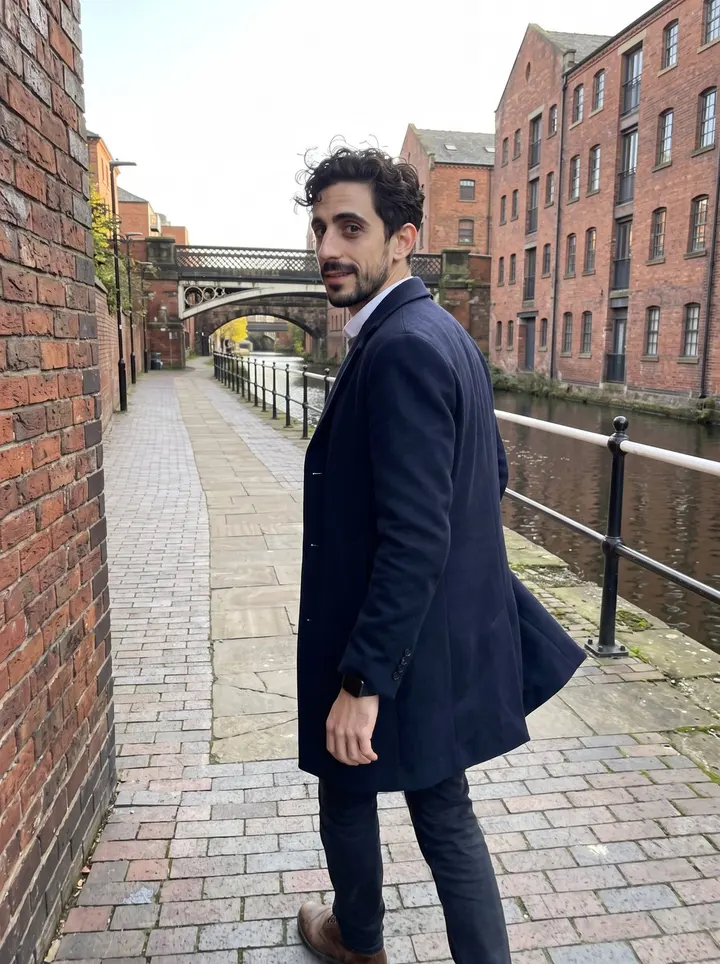 Hassan, AI character: the Castlefield canal towpath in Manchester, brick warehouses and still water behind him near golden hour
