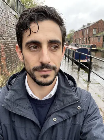 Hassan, AI character: the Rochdale Canal path after rain, wet brick walls and narrowboats behind him
