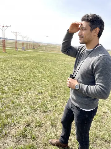 Luka, AI character: a grassy hill near the Denver airport approach path where he watches planes land on days off