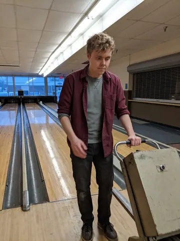 David, AI character: empty Scranton bowling alley at five in the morning, lanes just oiled, shoe-rental counter still closed
