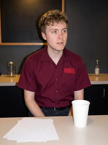 David, AI character: the bowling alley snack bar after league night, paper score sheets and a jar of pickled eggs on the counter