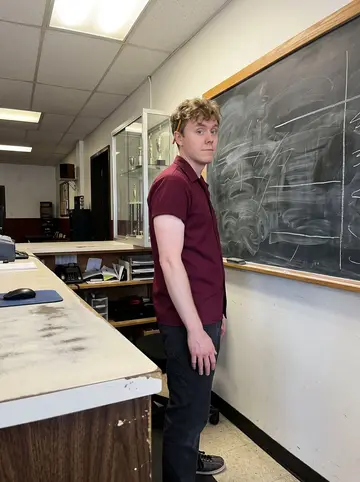 David, AI character: behind the bowling alley front desk, chalkboard league standings covering the wall behind him