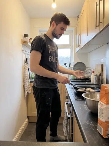 Orlando, AI character: his narrow Brighton flat kitchen, mixing bowl and griddle on the counter while he tries to make Welsh cakes