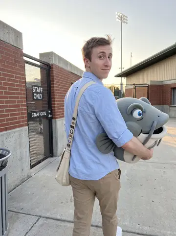 Braxton, AI character: outside the Boise minor-league ballpark after a weekend home game, near the staff gate with the field…