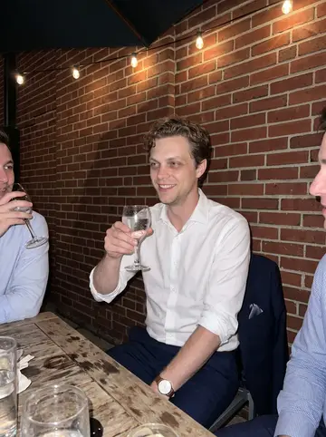 Forrest, AI character: a crowded restaurant patio in Hartford after a long trial-prep week, friends cropped at the edges of the frame