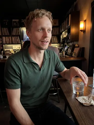 Chance, AI character: a small Denver record bar after a local vinyl night, standing near a high table with friends just out of frame
