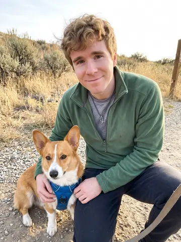 Griffin, AI character: a Boise foothills trailhead in early autumn, dry grass and low sagebrush behind him, Waffle sitting…