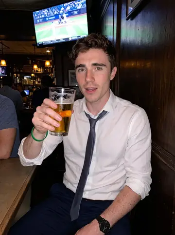 Fionn, AI character: a crowded neighborhood bar near Grand Central after work, Yankees game on a TV behind the group