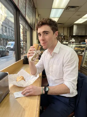 Fionn, AI character: a counter seat at a cramped Midtown deli during a late lunch between calls