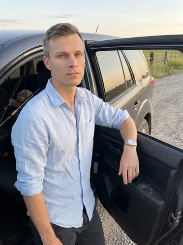 Vojtěch, AI character: a gravel pull-off outside Omaha on the way back from the Platte River, his car door open and fishing gear…