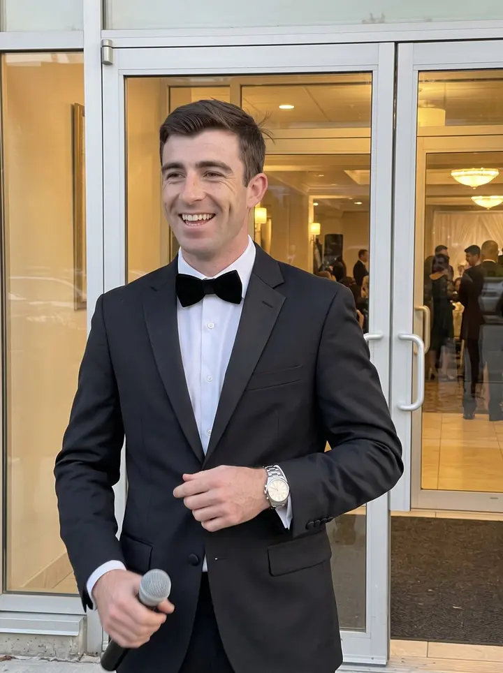 Casper, AI character: outside a Toronto banquet hall between wedding sets, glass doors and warm reception lights behind him