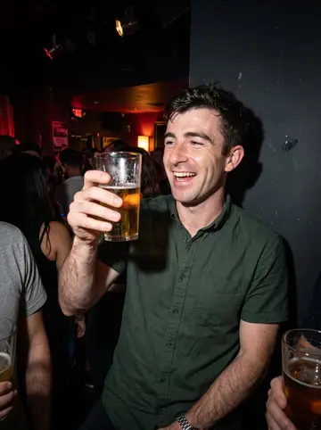 Casper, AI character: crowded Toronto karaoke bar after work, small stage lights and friends cropped at the edges