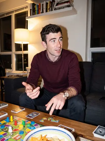 Casper, AI character: friend's apartment game night in Toronto, board game pieces and snack bowls on a coffee table