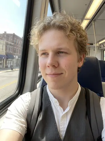 Vyacheslav, AI character: inside a Baltimore light rail car on the way to a daytime shift, city blocks passing through the window…