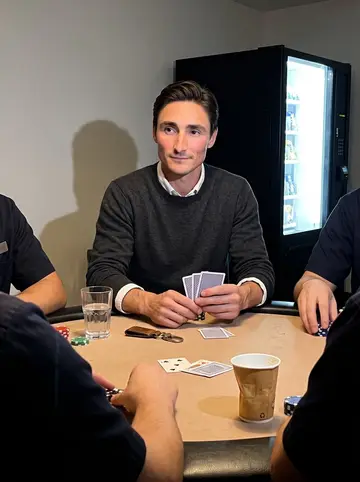 Otto, AI character: small staff break room behind the hotel lobby after midnight, three night porters cropped around a poker…