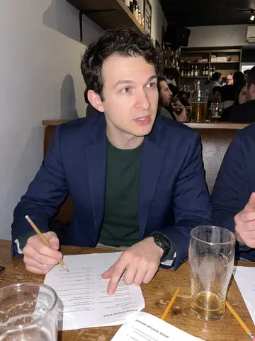 Veljko, AI character: a packed Toronto pub on Wednesday trivia night, score sheets and pint glasses on a sticky wooden table