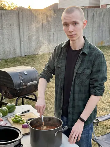 Jukka, AI character: small shared backyard behind his Oshawa rental, slow cooker chili ingredients on a folding table beside a…