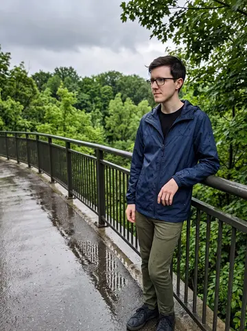 Petar, AI character: a wet Don Valley trail overlook after summer rain, green trees and a slick metal railing behind him