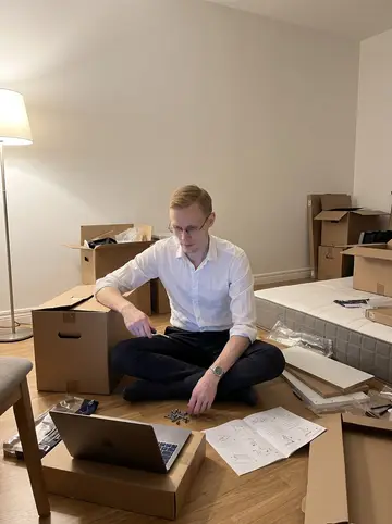 Oliver, AI character: his new half-empty Stockholm flat, one mattress on the floor, unopened boxes, and flat-pack furniture…