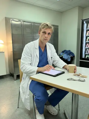 Matti, AI character: quiet hospital staff lounge in Houston after a long cardiac surgery shift, vending machine and lockers in…