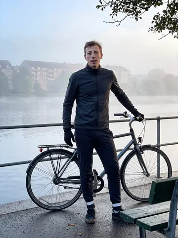 Nicolai, AI character: the path around Sortedam Lake just after dawn, his city bicycle leaned against the railing in light fog