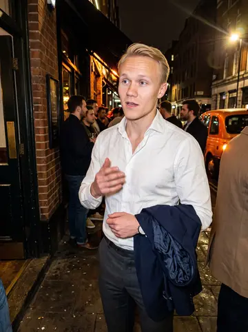 Antti, AI character: outside a crowded pub near Liverpool Street after a team drink, damp pavement and taxi lights behind him