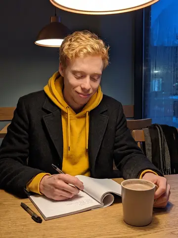Robin, AI character: small neighborhood cafe in Minneapolis on a cold night, a notebook of kids' jokes open beside a…