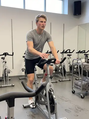 Theodor, AI character: the spin room of a neighborhood Chicago gym before the morning class, rows of bikes and a towel cart…