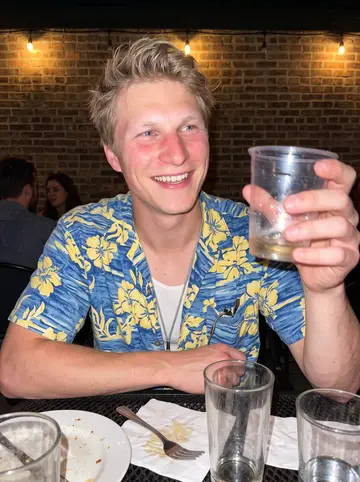Theodor, AI character: a crowded patio bar in Chicago after a rehearsal dinner, string lights and half-empty glasses on the table